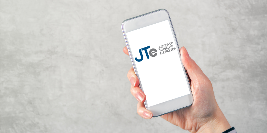 Foto de uma mão que segura um celular com o aplicativo do do JTe - Justiça do Trabalho eletrônica.