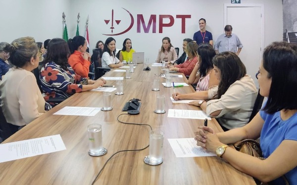 Foto de pessoas sentadas em uma mesa de reuniões.