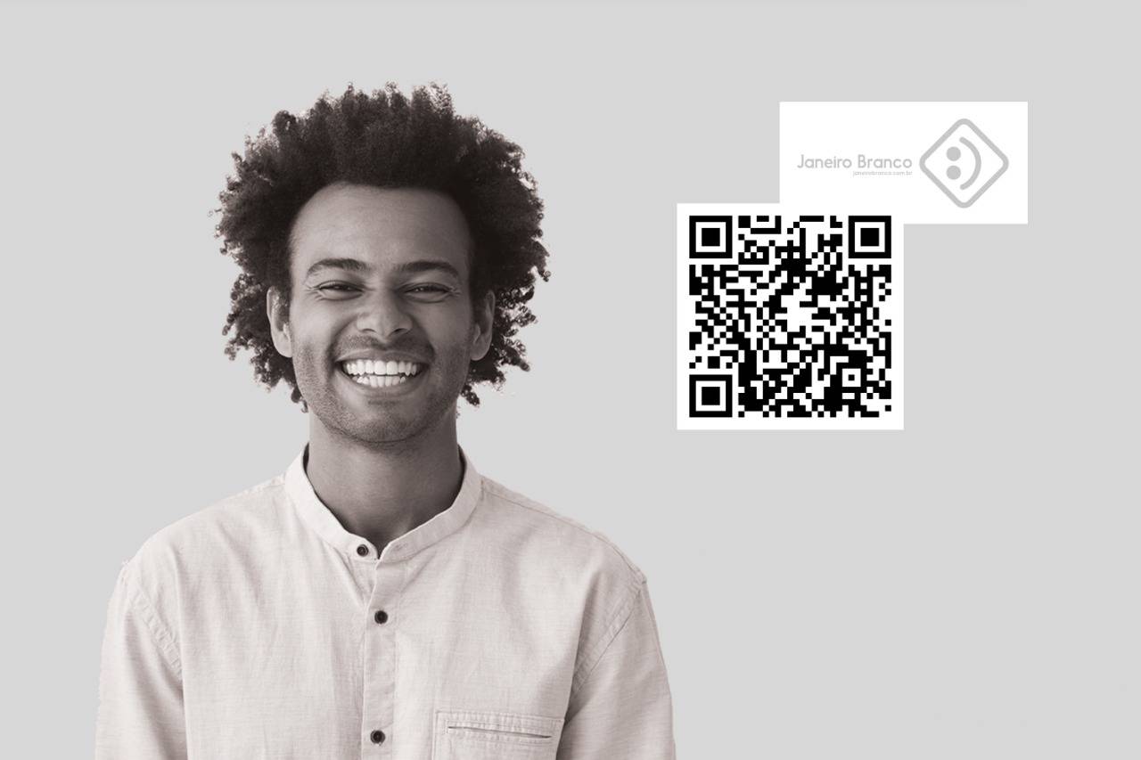 imagem ilustrativa da campanha. O modelo, um homem negro e jovem, sorri para a câmera, à direita da imagem está localizado um código QR, direcionando para o website da campanha