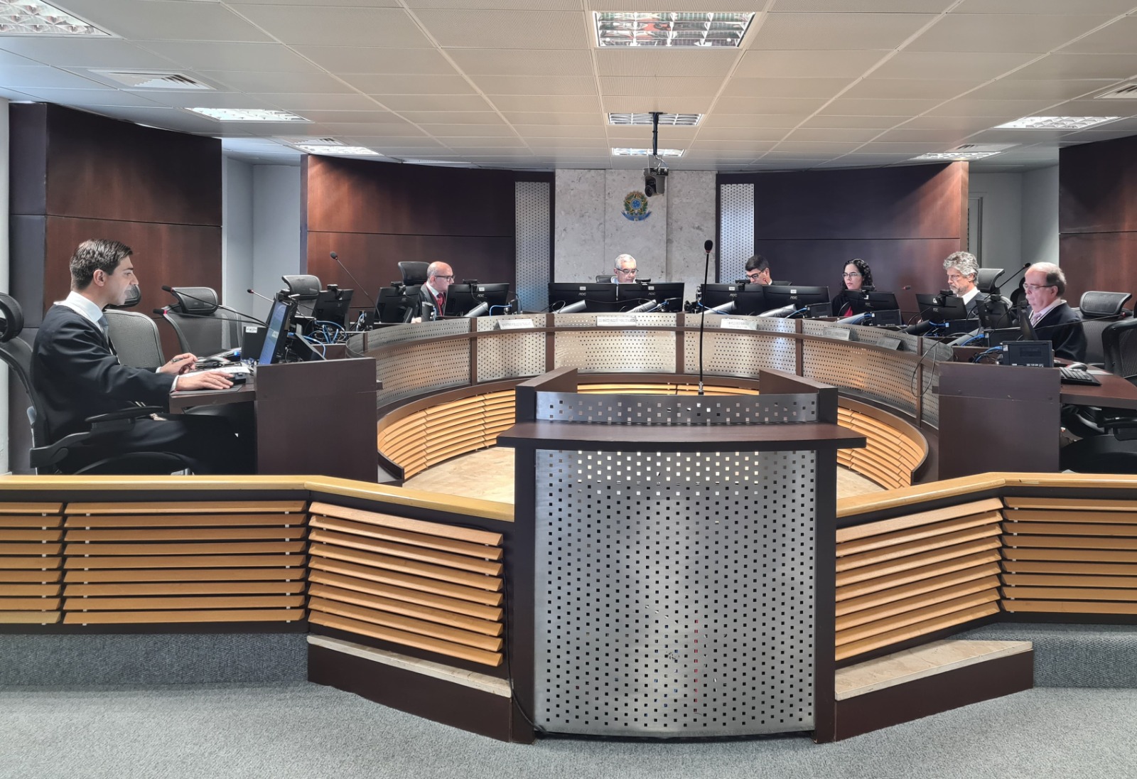 Imagem mostra membros da Primeira Turma do TRT-MS em sessão no Fórum Trabalhista. Dispostos no plenário estão Desembargadores, o Procurador do MPT e servidores do tribunal.