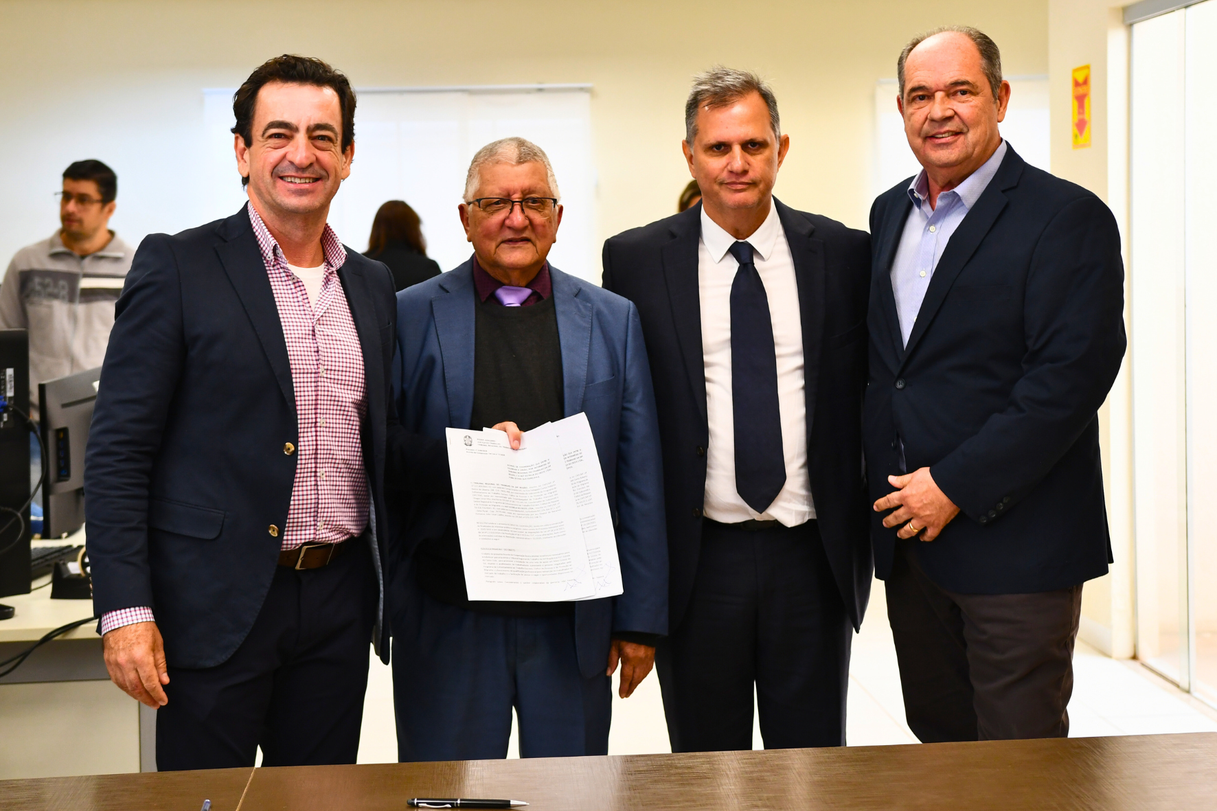 Pessoas em pé segurando termo de cooperação