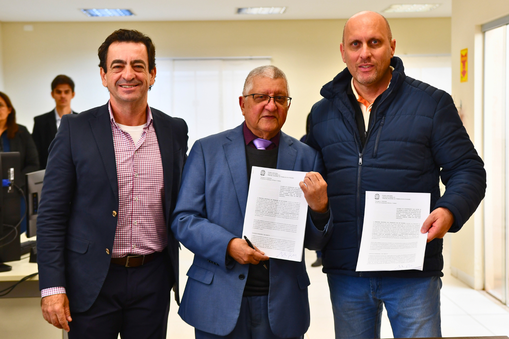 Pessoas em pé segurando termo de cooperação