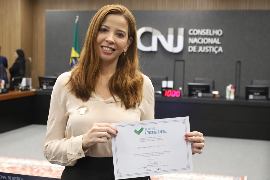 Foto da  juíza Déa Marisa Brandão Cubel Yule segurando um certificado.