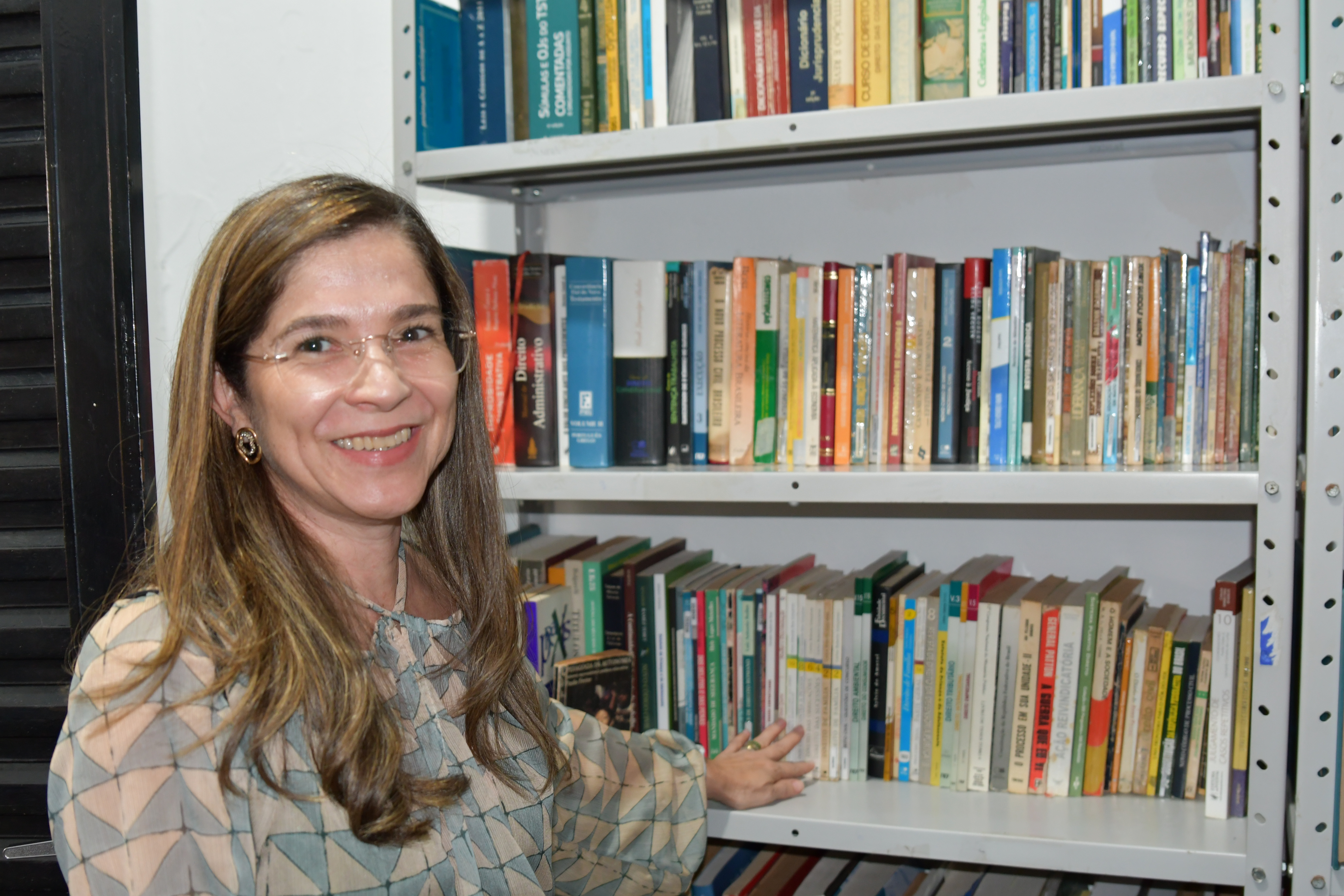 juíza Daniela e ao fundo estante com livros