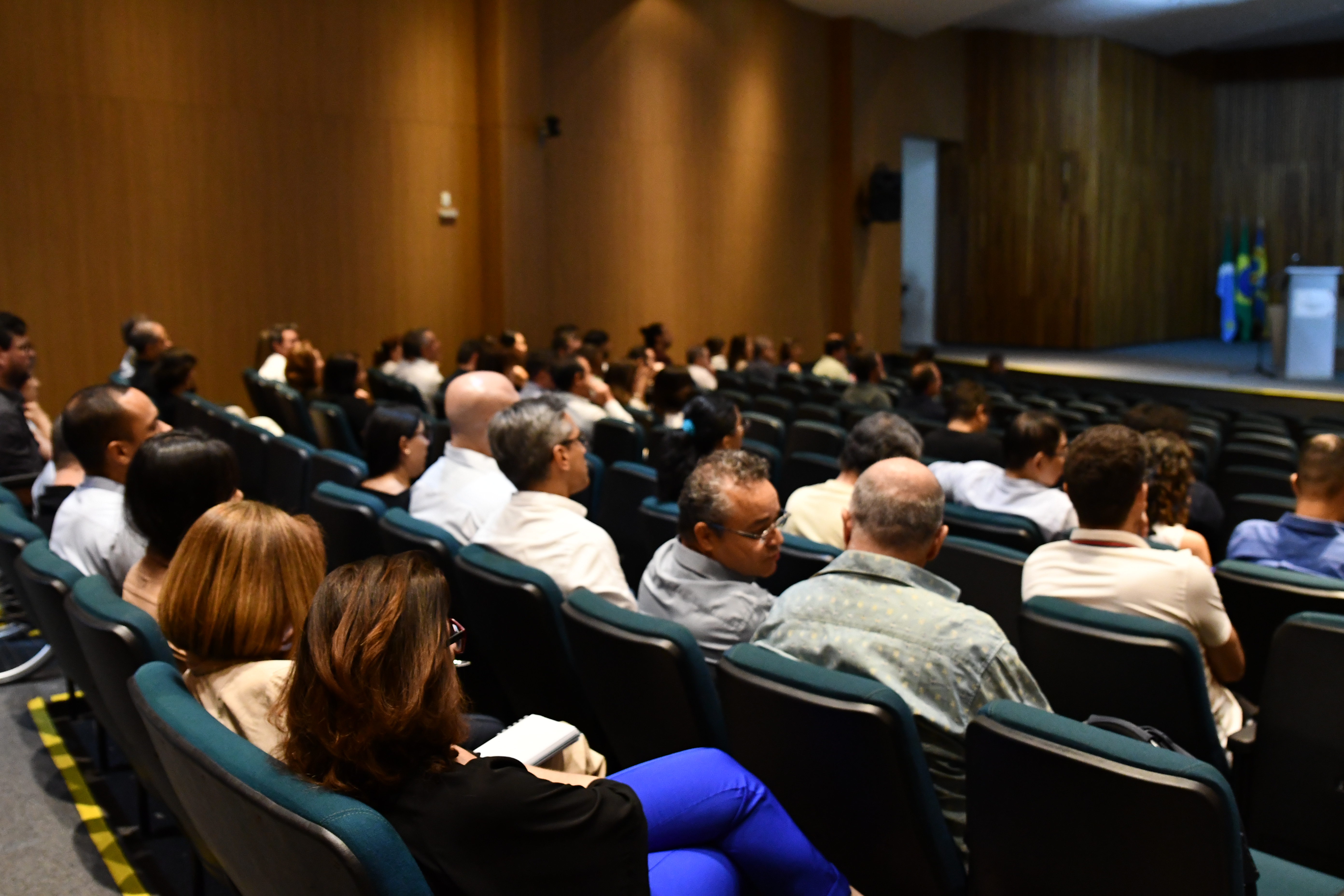 Servidores e servidoras sentados em poltronas durante palestra