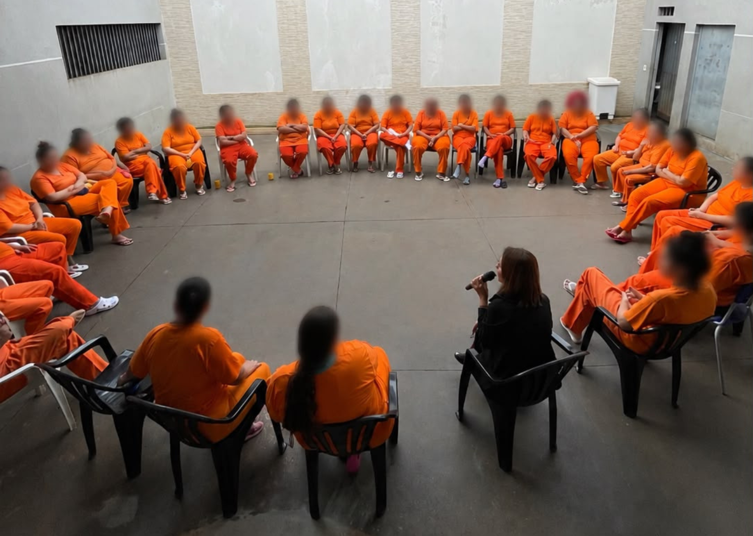 Mulheres privadas de liberdade sentadas em círculo durante palestra