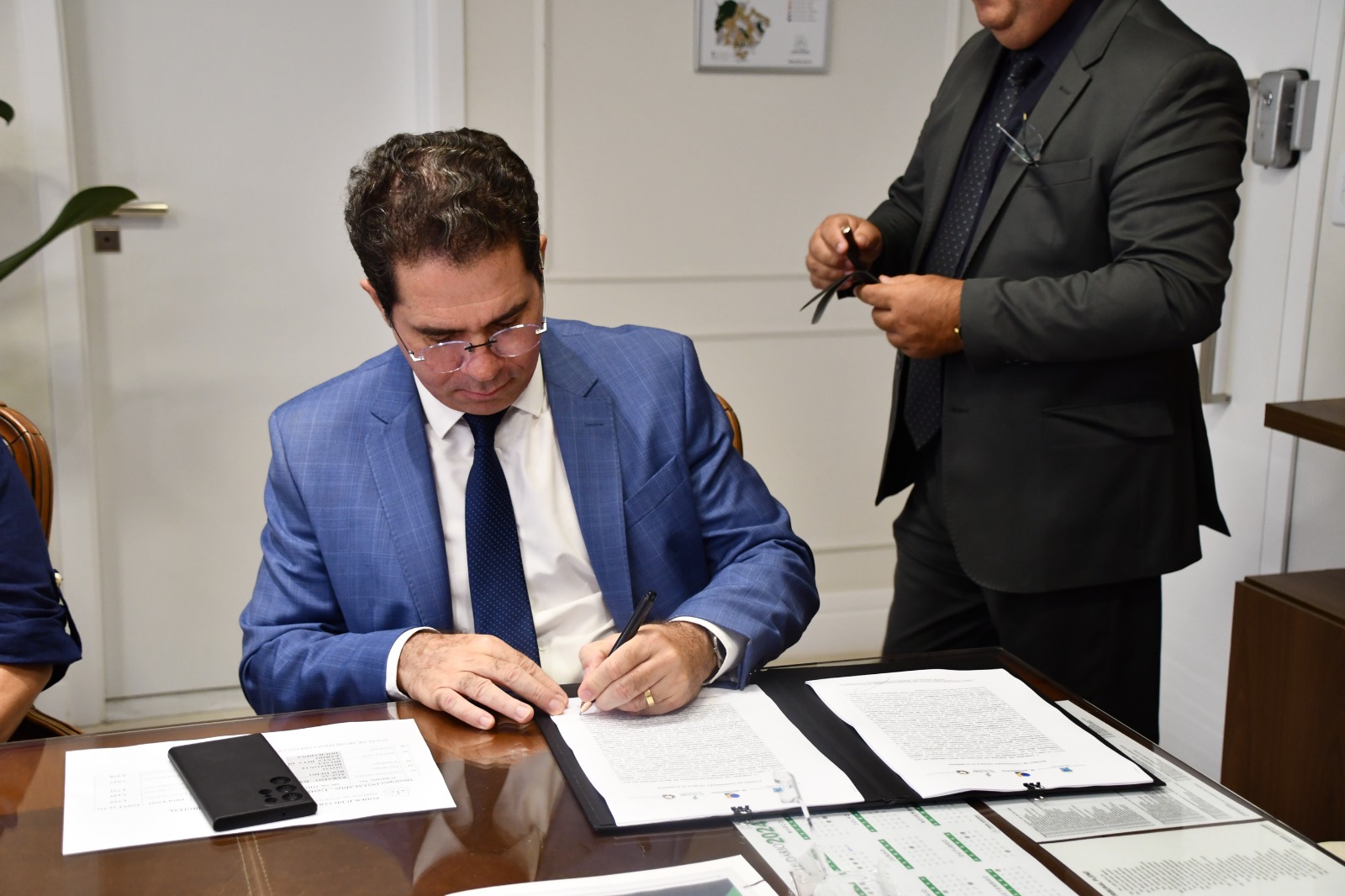 Presidente do TRT/MS veste terno azul e camisa branca e assina o termo 