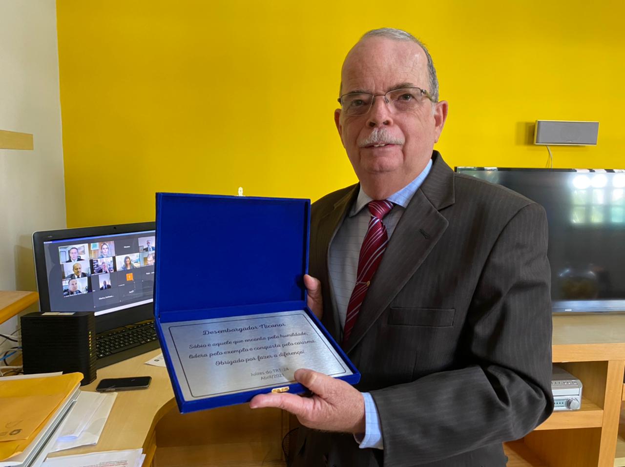 Foto do desembargador Nicanor de Araújo Lima segurando a placa de homenagem