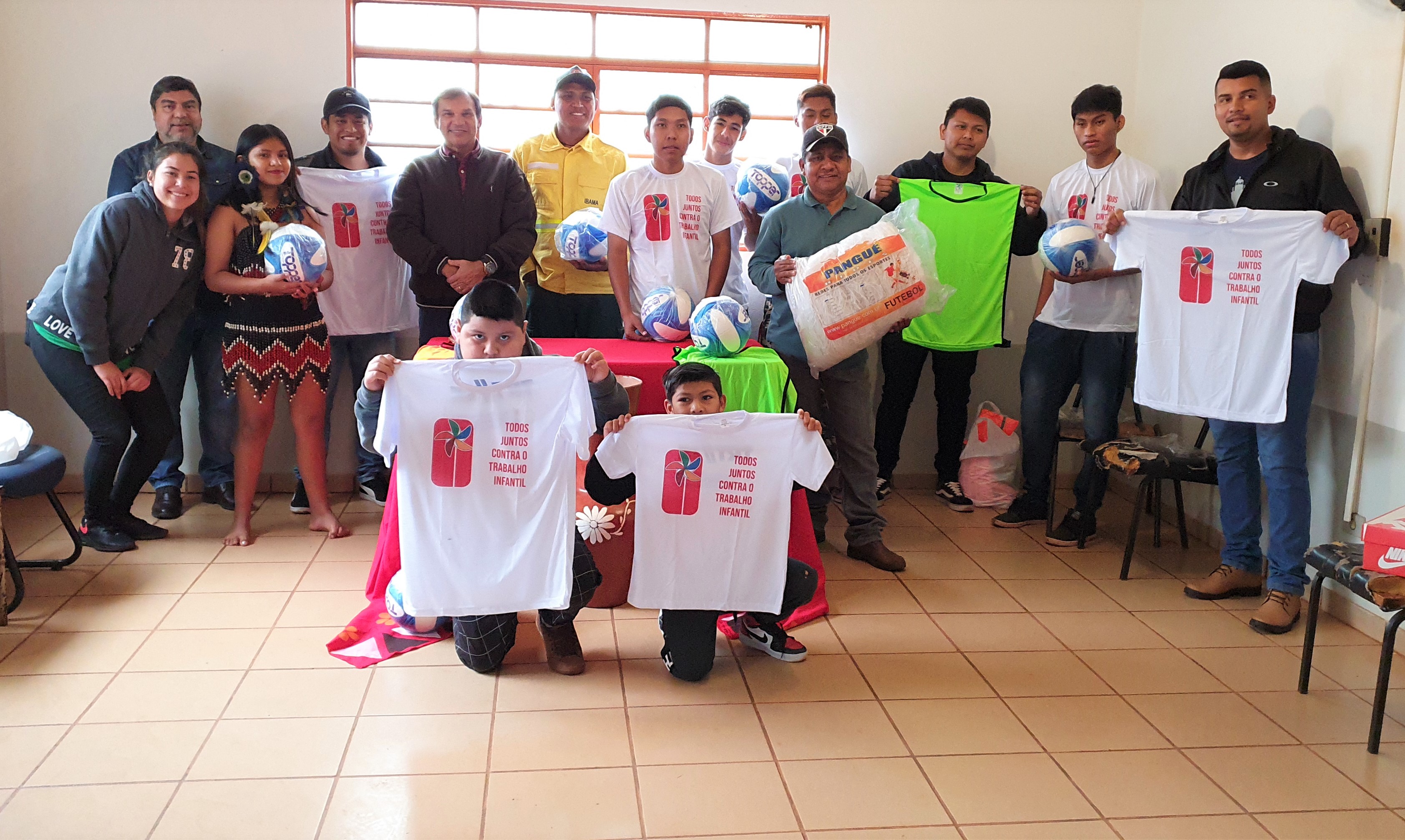 Foto das crianças e participantes após receberem os materiais.