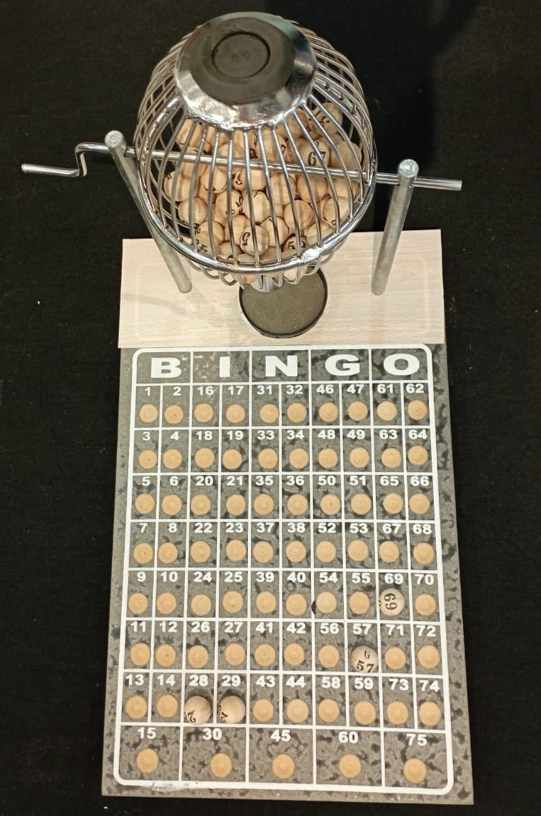Bingo, n.1, cromado com 75 peças, marca Três Reis. A peça foi adquirida em 1993, utilizada no período de 1993 a 1998, pela Seção de Distribuição de Feitos, subordinada ao Serviço de Cadastramento Processual.